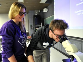 Postgraduate Emily Kyle (left) observes high school student Chad Sawyer as he peers through a microscope at Western University in London Ont. May 3, 2016. CHRIS MONTANINI\LONDONER\POSTMEDIA NETWORK