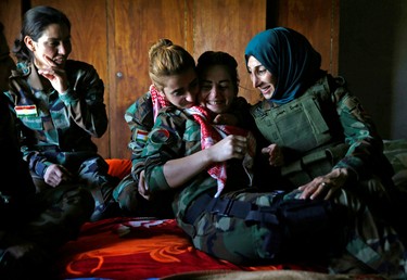 Yazidi female fighter Asema Dahir (L), 21, jokes with her comrades in a bedroom at a site near the frontline of the fight against Islamic State militants in Nawaran near Mosul,Iraq, April 20, 2016.  REUTERS/Ahmed Jadallah