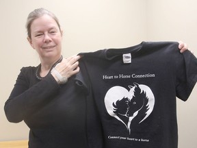 Dawn Sadler, in Kingston, Ont. on Wednesday, April 27, 2016, holds a t-shirt for her Heart to Horse Connection initiative, which promotes companionship between horses and humans without actually riding the animals. Michael Lea The Whig-Standard Postmedia Network