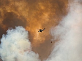 A helicopter battles a wildfire in Fort McMurray, Alta., on Wednesday May 4, 2016. The wildfire has already torched 1,600 structures in the evacuated oil hub of Fort McMurray and is poised to renew its attack in another day of scorching heat and strong winds. THE CANADIAN PRESS/Jason Franson