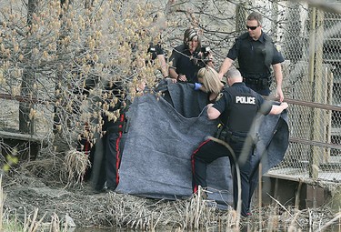 Police personnel use blankets to shield a body found behind Grant's Old Mill on Portage Avenue on Wednesday. On Thursday, police said they've tentatively confirmed the body was that of Cathy Curtis, 60, who disappeared after leaving nearby Grace Hospital on April 25. (Kevin King/Winnipeg Sun photo)