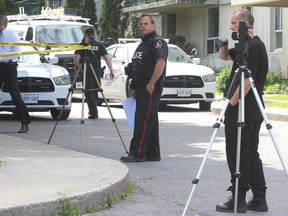 City police officers and detectives gather in front of a townhouse on Conacher Drive in Kingston, Ont. on Thurs., June 18, 2015 after the body of a woman was discovered inside. Michael Lea/The Whig-Standard/Postmedia Network