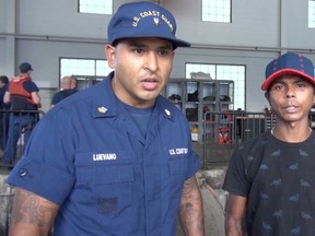 In this Wednesday, May 4, 2016 image taken from video, Petty Officer 2nd Class Simey Luevano, left, translates a statement from an unidentified mariner, right, after he was rescued at sea more than 2,000 miles southeast of Hawaii. (U.S. Coast Guard via AP)