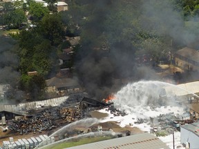 Firefighters pour water on a large blaze  on Thursday, May 5, 2016, in Houston. The four-alarm fire, which generated towering plumes of black smoke, began early Thursday morning at a custom packing and filling company in west Houston. The blaze caused various explosions that rattled the industrial area and surrounding neighborhoods. (Brett Coomer/Houston Chronicle via AP)