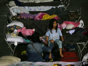 A young girl sits on a cot at a makeshift evacuee center in Lac la Biche on May 5, 2016.