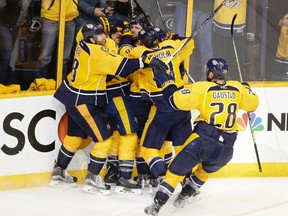 Nashville Predators forward Mike Fisher, top centre, is mobbed by teammates after scoring the winning goal against the San Jose Sharks during the third overtime period in Game 4 of their playoff series in Nashville, Tenn., on May 6, 2016. The Predators won 4-3 in triple overtime to even the series 2-2. (AP Photo/Mark Humphrey)