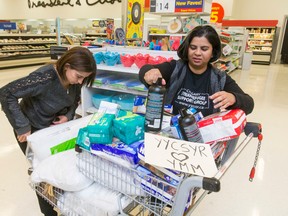 Rita Khanchet, left, and Saima Jamal arrange supplies in an overflowing cart at the Rundle Superstore in Calgary on Thursday, May 5, 2016. Through the Syrian Refugee Support Group, Syrian refugees were buying daily essentials to help victims of the Fort McMurray wildfire devastation. Lyle Aspinall/Postmedia Network