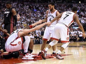 Toronto Raptors center guards Cory Joseph and Kyle Lowry pull centre Jonas Valanciunas to his feet after he was fouled against Miami Heat  in Game 2 of the second round of the NBA Playoffs at Air Canada Centre in Toronto on May 5, 2016. (Dan Hamilton/USA TODAY Sports)