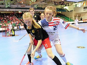 Team Canada's Emily Lange keeps a U.S. opponent at bay during IFF U19 women's floorball world championship action Saturday night at Yardmen Arena. (Aaron Bell photo)
