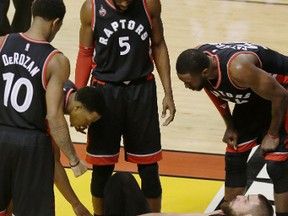 Toronto Raptors centre Jonas Valanciunas (17) holds onto his right ankle as his teammates assist during the second half of Game 3 of an NBA second-round playoff basketball series against the Miami Heat, Saturday, May 7, 2016, in Miami. (AP Photo/Alan Diaz)