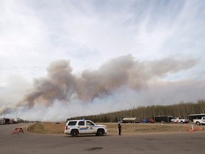 Smoke billows from wildfires as RCMP man a checkpoint on the highway to Fort McMurray, Alberta wildfires that are still burning out of control Saturday, May 7, 2016.THE CANADIAN PRESS/Ryan Remiorz