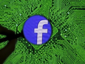 Facebook's logo is seen through a magnifier in front of a displayed PC motherboard, in this illustration taken April 11, 2016. REUTERS/Dado Ruvic/Illustration