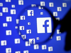 A man poses with a magnifier in front of a Facebook logo on display in this illustration taken in Sarajevo, Bosnia and Herzegovina, December 16, 2015. (REUTERS/Dado Ruvic)