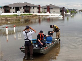 Members of the RCMP return from a boat patrol of a still flooded neighborhood in High River, Alta., on July 4, 2013.