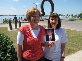 Sisters Leah Nielsen and Stacy Cattran stand at the Victims of Chemical Valley Memorial in Centennial Park in this Observer file photo from 2011 — holding a photograph of their father Bill Coulbeck, who died from asbestos-caused mesothelioma. Both sisters were delighted to hear news Wednesday that the Canadian government is moving forward on an asbestos ban. (Handout/Sarnia Observer/Postmedia Network)