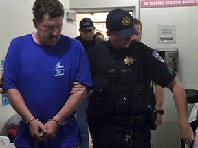 This Wednesday, May 11, 2016, photo released by the Clovis Police Department shows Dave Thomas McCann, centre left, being escorted by officers in Clovis, Calif. McCann, a British man suspected of killing his wife and mother-in-law with a knife at their central California home, has been arrested after four days on the run, police said Wednesday. (Clovis Police Department via AP)