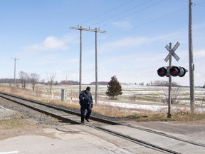 An OPP investigator takes photos after a VIA Rail passenger train collided with a car, killing it's two occupants, at a level crossing with cross bucks and lights on Melbourne Drive north of Melbourne, Ont. on Monday April 4, 2016.  The driver and a passenger of a car, which was travelling southbound on the county road shortly after 10:30 a.m., were pronounced dead a the scene, according to OPP.  None of the 88 passengers on train 72, en route from Windsor to London and Toronto, were injured.  (CRAIG GLOVER, The London Free Press)