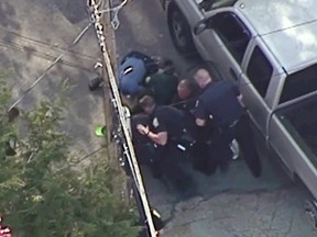 This aerial image made from a helicopter video provided by WHDH shows several officers pummeling Richard Simone, who had exited his vehicle and kneeled on the ground after a high-speed police pursuit, in Nashua, N.H., Wednesday, May 11, 2016. The chase went through several towns before ending in Nashua. (Courtesy WHDH via AP)