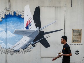 In this Tuesday, Feb. 23, 2016, file photo, a waiter walks past a mural of flight MH370 in Shah Alam outside Kuala Lumpur, Malaysia. Malaysia's government said Thursday, May 12, 2016, that two more pieces of debris, discovered in South Africa and Rodrigues Island off Mauritius, were "almost certainly" from Flight 370, which mysteriously disappeared more than two years ago with 239 people on board.(AP Photo/Joshua Paul, File)