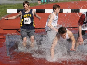 Runners splash down in the water hazard during competition in the open boys 2000m steeplechase at Wednesday's Bay of Quinte track and field championships at MAS Park. (Tim Meeks/The Intelligencer)