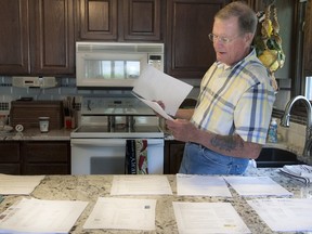 In this photo taken Monday, May 9, 2016, Chuck Zellers, of Lincoln, Neb., looks through some of the records and paperwork he has accumulated while trying to fix a Social Security error that declared him deceased. (Gwyneth Roberts/The Journal-Star via AP)