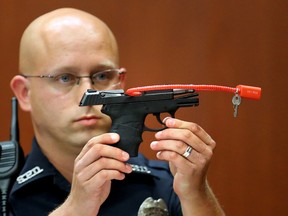 In this June 28, 2013, file photo, Sanford police officer Timothy Smith holds up the gun that was used to kill Trayvon Martin, while testifying in the George Zimmerman trial, in Seminole circuit court in Sanford, Fla. The pistol former neighborhood watch volunteer Zimmerman used in the fatal shooting of Martin went up for auction online. (AP Photo/Orlando Sentinel, Joe Burbank, Pool, File)