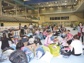 Volunteers sort through the clothing donations flooding into the TransAlta Tri Leisure Centre on May 5. Fort McMurray evacuees staying in the tri-region said they have been overwhelmed by the generosity of the community. - Photo by Marcia Love