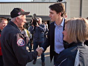 Prime Minister Justin Trudeau shakes hands with Fort McMurray fire chief Darby Allen as Alberta Premier Rachel Notley (right) looks on in Edmonton, Friday, May 13, 2016. THE CANADIAN PRESS/Jason Franson