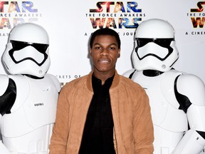 John Boyega poses alongside two stormtroopers attending the U.K. Gala Screening of 'Secrets of the Force Awakens : A Cinematic Journey', in London, on March 29, 2016. (Ian West/PA via AP)