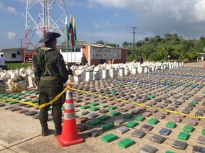 A Colombian national policeman stands guard in front of packages of cocaine, which were confiscated in Turbo province near the border with Panama, May 15, 2016.  Colombian  Police/Handout via REUTERS