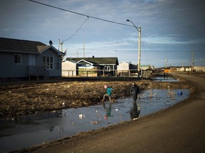 Indigenous children play in a water- filled ditch in the northern Ontario First Nations reserve in Attawapiskat, Ont., on Tuesday, April 19, 2016. In many ways, Attawapiskat - population 2,100 - has all the trappings of any small town, including older folk lamenting the changing of the times. THE CANADIAN PRESS/Nathan Denette