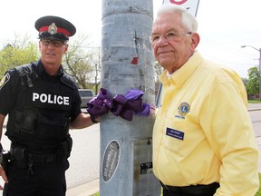 Sarnia Police Const. Chris Moxley and Art Speed with the Lambton Drug Awareness Action Committee tie a purple ribbon at the Exmouth Street at Indian Road intersection in Sarnia Tuesday. The committee's annual Purple Ribbon Campaign to create awareness about alcohol-related crashes runs until May 31. Tyler Kula/Sarnia Observer/Postmedia Network