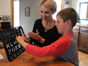 Rowan Esser, 10, spells out his mother Trish's name on his stencil board at their Petrolia home Tuesday. The St. Philip's student, who has non-verbal autism, has found his own voice for the first time with the use of the rapid prompting method, a communication system designed for people with autism and other disorders. (Barbara Simpson, The Observer)