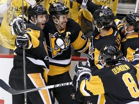 Penguins’ Sidney Crosby (second from left) celebrates with teammates after scoring the game-winning in OT on Monday. (AP)