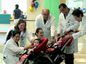 In this photo provided by Driscoll Children's Hospital, from left, Driscoll Children’s Hospital physicians Angelina Bhandari, Jane Lyon, Vanessa Dimas, Karl Maher, Omar Cruz-Diaz, and Miguel DeLeon, say goodbye to former conjoined twins Scarlett and Ximena Hernandez-Torres, who left Driscoll Children’s Hospital in Corpus Christi on Wednesday morning, May 18, 2016, five weeks after their separation surgery. (Driscoll Children's Hospital via AP)