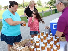 In this file photo from 2015, Andrea Sarra and her daughter Giselle purchase honey from Six Pines Farm owner Lisa Pownall at the Point Edward Moonlight Farmers' Market. The Thursday markets are set to begin again May 26, and run weekly from 4 p.m. to 8 p.m, in the Waterfront Park, next to the Blue Water Bridge. File photo/Sarnia Observer/Postmedia Network