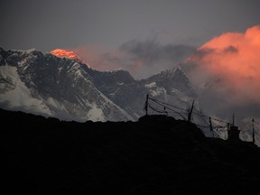 In this Saturday, Nov. 7, 2015 file photo, the last light of the sun sets on Mount Everest, as seen from Pangboche, Nepal.  High winds have delayed dozens of climbers trying to reach the summit of Mount Everest, a mountaineering official said Wednesday, May 18, 2016. The winds have made it difficult for the climbers to make their attempts for the summit but posed no immediate danger, said Gyanendra Shrestha, an official in Nepal's Mountaineering Department who is at base camp on Everest.(AP Photo/Tashi Sherpa, File)
