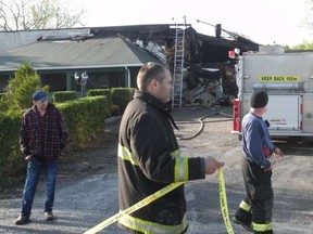 Bonnie Glen Pavilion owner Michel Diotte, left, watches as North Glengarry firefighters clean up the scene Friday morning following a fire that began Thursday night. GREG PEERENBOOM / GREG PEERENBOOM/STANDARD-FREEHOLDER
