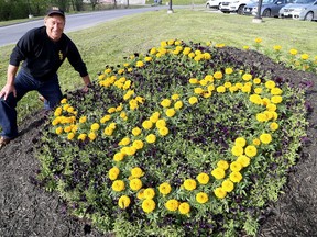 Gary Shultz, a student when La Salle Secondary School opened in 1968, kneels next to a 50th anniversary flower garden at the school in Kingston. (Ian MacAlpine/The Whig-Standard)