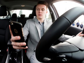 Professional race car driver Parker Thompson, 17, checks his phone while posing for a photo during a Province of Alberta press conference on distracted driving, at the Edmonton Expo Centre, in Edmonton Alta. on Monday Feb. 8, 2016. Photo by David Bloom