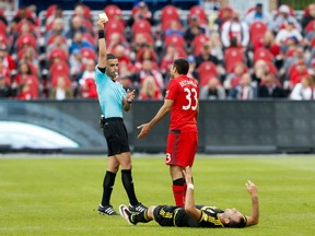 TFC defender Steven Beitashour reacts in disbelief as he is given a yellow card by referee Nima Saghafi yesterday at BMO Field while Columbus’ Justin Meram lies on the turf. (USA Today Sports)
