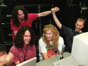 In this July 24, 1997, file photo, lead guitarist Marty Friedman, left, and lead singer/guitarist Dave Mustaine, centre, field questions while bassist David Ellefson, right, high-fives drummer Nick Menza, back left, during a live chat on the internet held at The Joint inside the Hard Rock hotel-casino in Las Vegas. (Ethan Miller/Las Vegas Sun via AP)