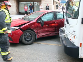 A Winnipeg firefighter examines damage following a collision between a car and a transit bus at Graham and Hargrave in Winnipeg, Man. Sunday, May 22, 2016. (Brian Donogh/Winnipeg Sun/Postmedia Network)