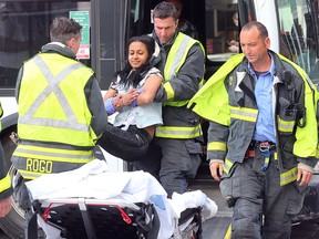 Winnipeg Fire Paramedic Service personnel carry an injured woman from a bus following a collision between a car and a transit bus at Graham and Hargrave in Winnipeg, Man. Sunday, May 22, 2016. Police said three people were taken to hospital but were not believed to have suffered serious injuries. (Brian Donogh/Winnipeg Sun/Postmedia Network)