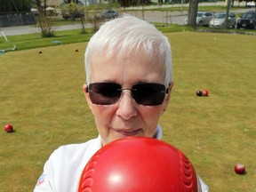 Pat Gibbs holds a bowl at the Trenton Lawn Bowling Club. They're both weighted and have somewhat flattened sides to send them on curving routes across the green.