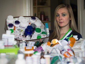 Paige Spencer, 21, who suffers from chronic Lyme disease, holds her daily dosage of prescription medications she has to ingest. In the foreground are the empty drug containers containing medicine she has had to take to control her symptoms. (Stan Behal/Toronto Sun)