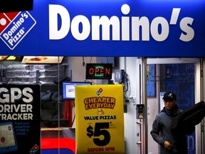 A worker carries a pizza for delivery as he exits a Domino's pizza store in Sydney, Australia, in this August 12, 2015 file photo. Domino's is expected to announce Q3 earnings on October 8, 2015.  REUTERS/David Gray/Files