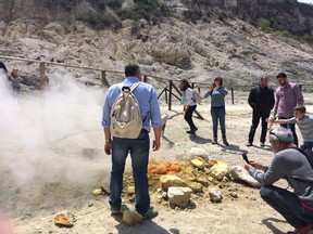 In this photo taken on Saturday, April 30, 2016, visitors look at steaming fumarolas at the Solfatara crater bed, in the Phlegraean Fields near Naples, Italy. Fields -- Campi Flegrei in Italian -- are a sprawling constellation of ancient volcanic centers. (AP Photo/Frances D'Emilio)