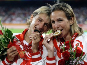Russia's gold medal winner Gulnara Galkina-Samitova (left) and bronze medal winner Ekaterina Volkova (right) bite their medals after the women's 3000-metre steeplechase at the Beijing 2008 Olympics in Beijing on Aug. 17, 2008. Fourteen Russian athletes who competed in the Beijing Olympics tested positive in the reanalysis of their doping samples, Russian state television reported Tuesday, May 24, 2016. (Petr David Josek/AP Photo/Files)