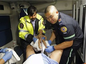 Paramedic Mike Cheung (right) delivers a baby in the back of an ambulance with assistance from Postmedia reporter Ameya Charnalia (left) during a simulation training exercise held in Edmonton on May 24, 2016. Larry Wong / POSTMEDIA